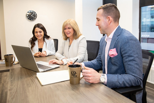 Auditor General, Kim Adair, consulting with diverse coworkers in office.